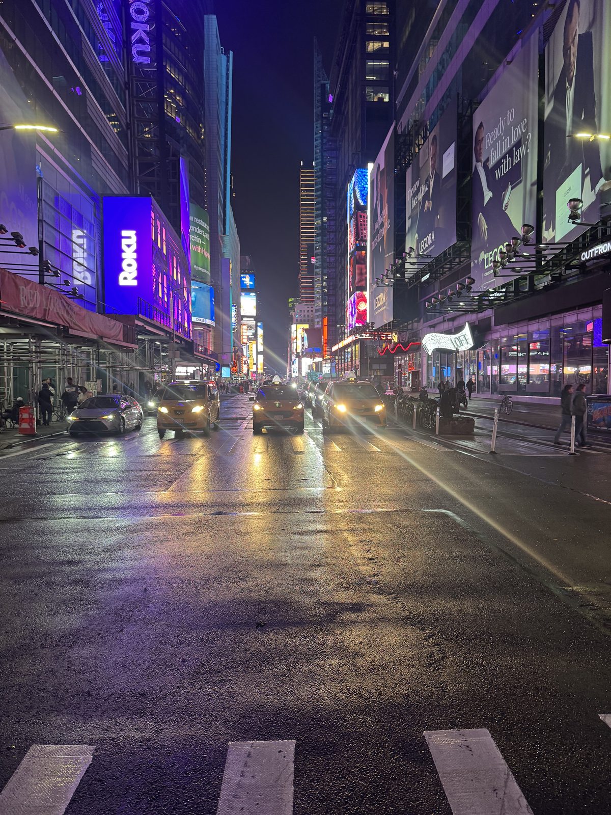 Times Square at night, wet streets and Roku billboards